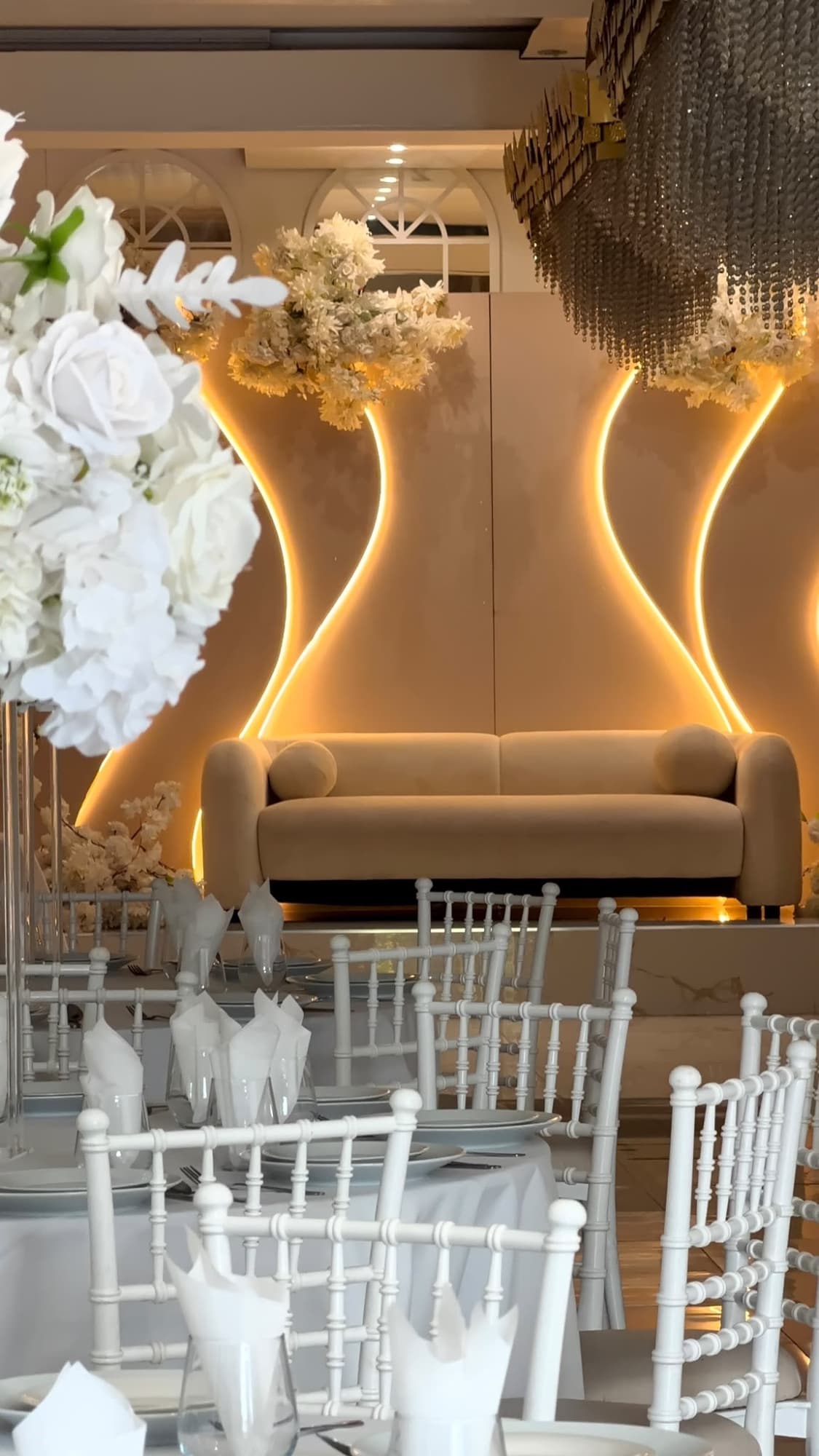 A close view of a laid table and white chairs, with the lit stage behind